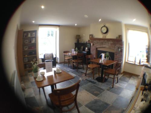 a dining room with tables and chairs and a fireplace at Deri-Down Guest House in Abergavenny