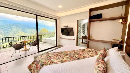 a bedroom with a bed and a balcony with a view at Hotel El Mirador del Cocora in Salento