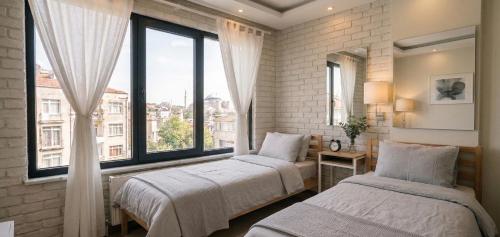 two beds in a room with a large window at pınar apart hotel in Kapuluören