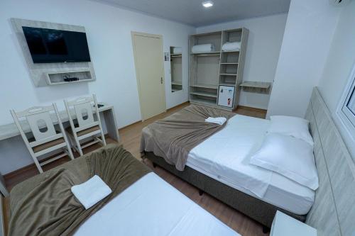 a small room with two beds and a tv at Pousada Prime Gramado in Gramado