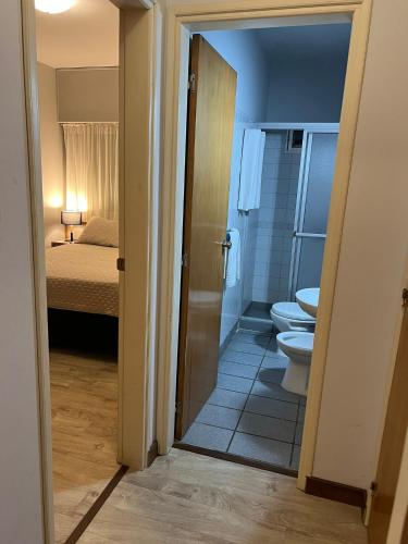 a bathroom with a toilet and a bedroom with a bed at Hotel Italiano in Colonia del Sacramento