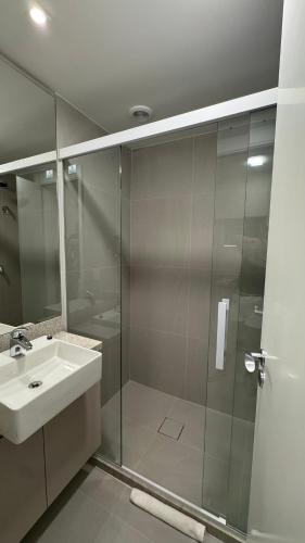 a bathroom with a glass shower and a sink at Cond Skyline in Porto Alegre