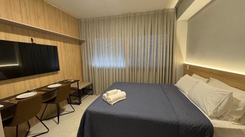 a hotel room with a bed and a desk and a television at Cond Skyline in Porto Alegre