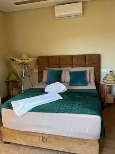 a bedroom with a large bed with blue pillows at Lake House Boulaouane in Douar Annbirat