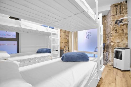 a bedroom with two bunk beds and a stone wall at Albergue San Nicolás in Logroño