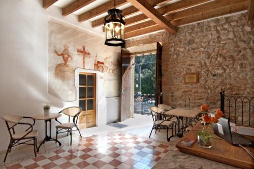 Habitación con mesas, sillas y pared de piedra. en Petit Hotel Hostatgeria La Victoria, en Alcudia