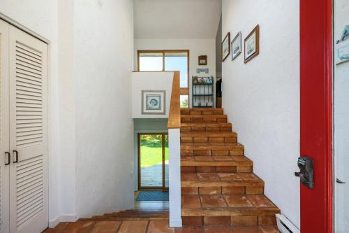 a staircase in a house with a red door at Sunset Serenade in Truro