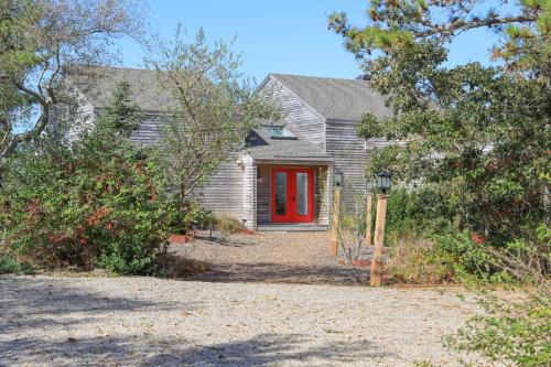 a house with a red door and some trees at Sunset Serenade in Truro