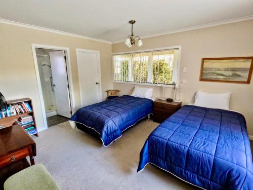 a bedroom with two beds and a desk and a window at Almost Country in Taupo