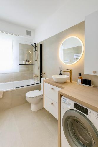 a bathroom with a washing machine and a sink at Sweet Home - Cocon élégant climatisé, piscine été, balcon & parking privé in Chambéry