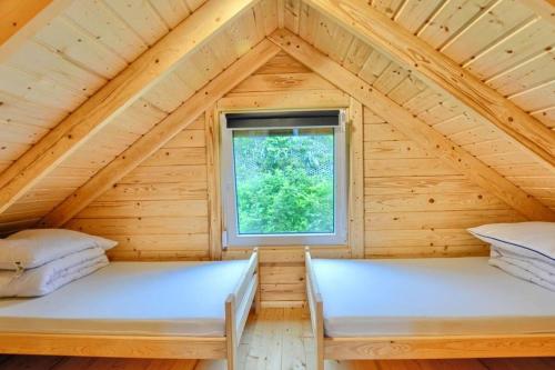 two beds in a wooden room with a window at DOMKI u WILKA - Solina Centrum in Solina