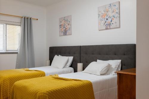 two beds in a room with yellow sheets at Apartamentos do Triângulo in Velas