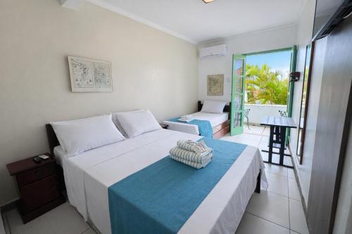 a bedroom with a bed with a blue and white blanket at Pousada Estalagem do Porto in Arraial do Cabo