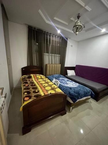 a bedroom with two twin beds and a couch at Hsan Bouslimi in Ez Zahra