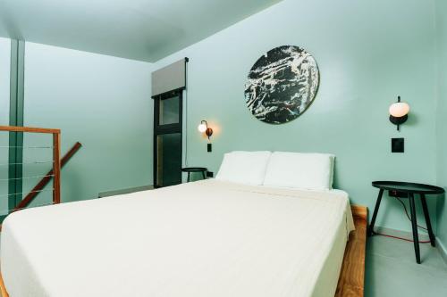 a bedroom with a white bed and a blue wall at Stylish Tiny Home with Sea View and Bathtub in Alto del Espino Prieto