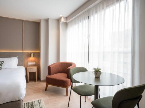 a hotel room with a bed and a table and chairs at Bomma House - Parque 93 in Bogotá
