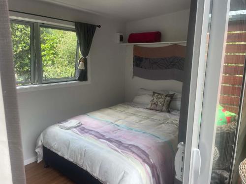 a small bed in a small room with two windows at Beach Bach Whangaumu Bay Tutukaka in Tutukaka