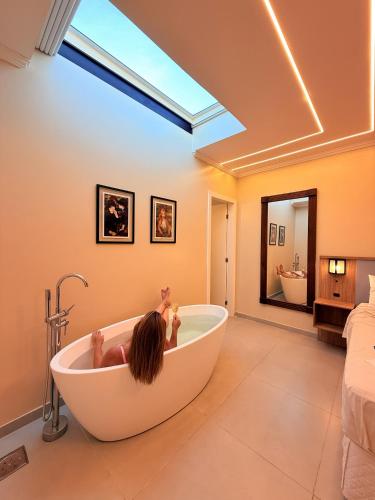 a little girl laying in a bath tub in a bathroom at Pousada Estalagem do Porto in Arraial do Cabo