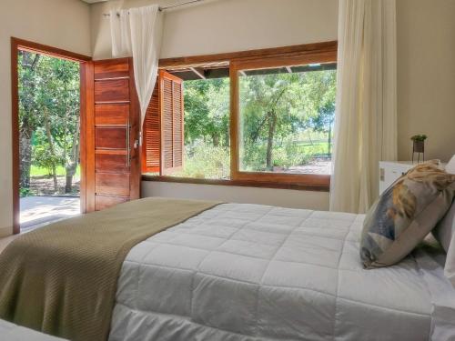 a bedroom with a large bed and a large window at CasaAnacã Ecolounge in Bonito