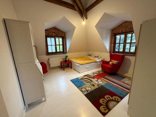 a small room with a bed and a red chair at Dako Apartment, Luxurious, Cosy, Spacious in Rzeszów