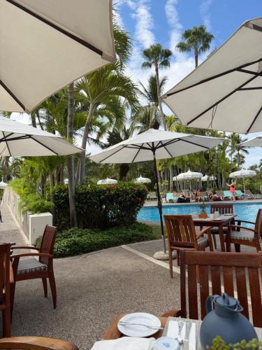 a restaurant with tables and umbrellas next to a pool at 2bd apartment in Nuevo Vallarta