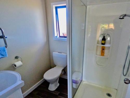a white bathroom with a toilet and a shower at Almost Country in Taupo