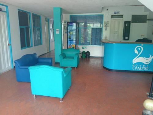 a lobby with two blue chairs and a bar at Hotel Danubio Azul in Yopal