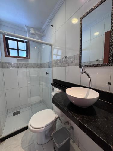 a bathroom with a sink and a toilet and a mirror at Estalagem 11 Suites in Arraial do Cabo