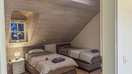 two beds in a small bedroom with a wooden ceiling at Ferienwohnung Sonnentälchen in Konz