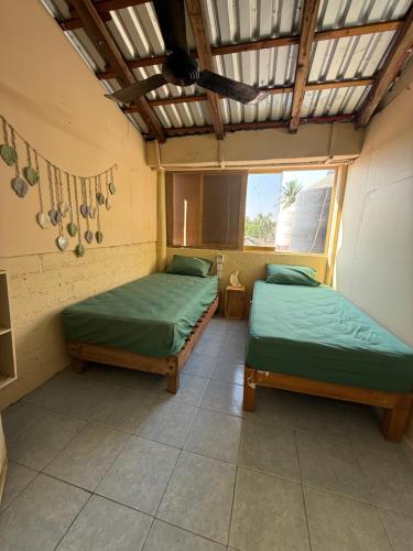 two twin beds in a room with a roof at TerraZica hostal in Brisas de Zicatela