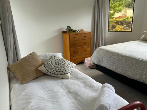 a bedroom with two beds and a dresser with a window at Stunning Mount beachside location in Mount Maunganui