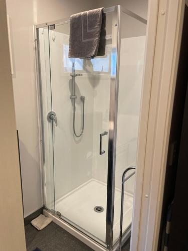 a shower with a glass door in a bathroom at Quiet restful unit with seaviews in Auckland