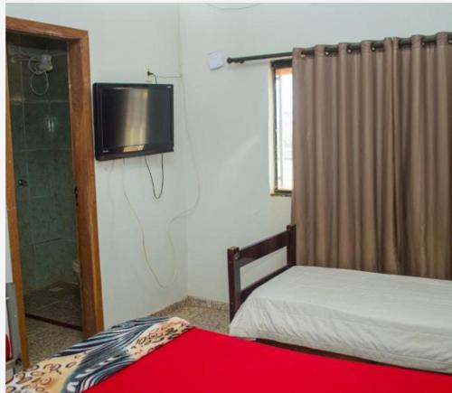 a bedroom with a bed and a tv on the wall at Hotel Pousada na Br 040 in Valparaíso de Goiás