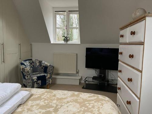 a bedroom with a bed and a tv and a chair at Silsoe Cottage BB Master Suite in Bedford