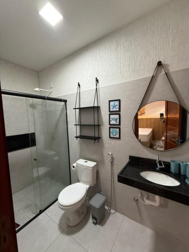 a bathroom with a toilet and a sink and a mirror at Apartamento a 50m da praia em Camocim CE in Camocim