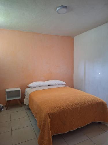a bedroom with a bed with an orange blanket at Departamento cerca de la playa in Puerto Vallarta