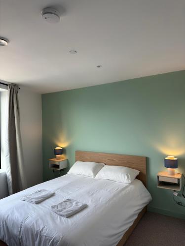 a bedroom with a large white bed with two lamps at 02 Arena, Specious Apartments in London