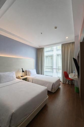 a hotel room with two beds and a desk at DK Belstar Hotel Belitung in Tanjungpandan