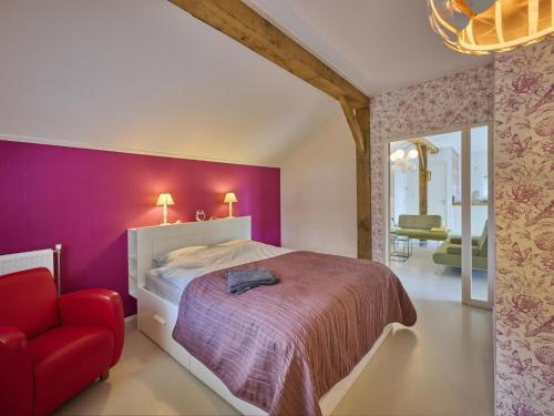 a bedroom with a bed and a red chair at Design Farmers Barn Twente in Haaksbergen