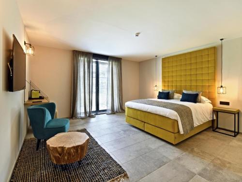 a hotel room with a bed and a blue chair at Villa with Pool & Suites for 12 Guests in Durbuy