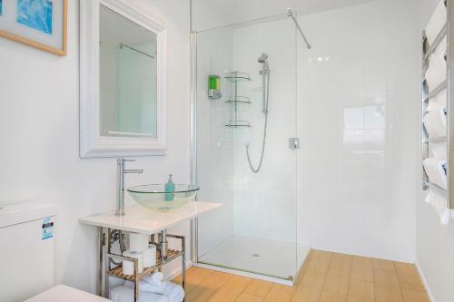 a white bathroom with a shower with a glass bowl on a table at Bruny Island Escapes and Hotel Bruny in Alonnah