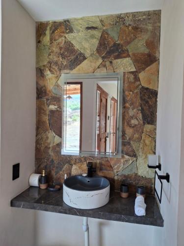 a bathroom sink with a mirror on a stone wall at Cabaña los amarillos in Huacalera