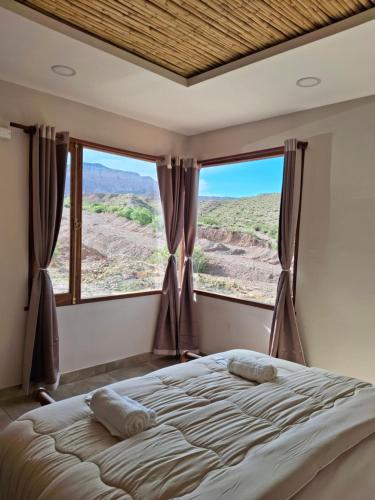 a bedroom with a bed and a large window at Cabaña los amarillos in Huacalera