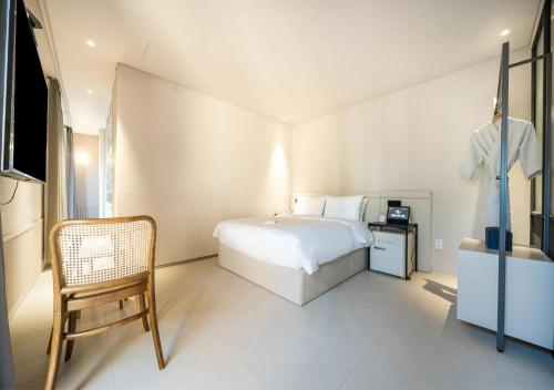 a bedroom with a bed and a chair in it at 부산 대연동 뮤트호텔 in Kwangan-dong