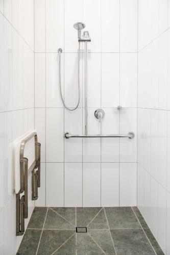 a shower in a bathroom with white tiles at Avenue WEST Studio Units in Toowoomba