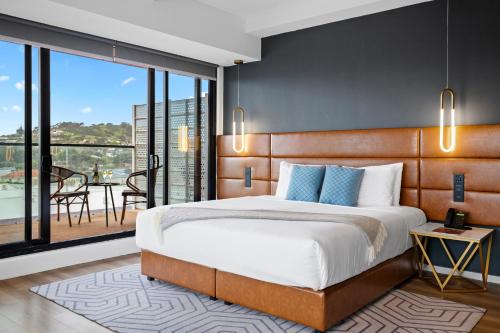 a bedroom with a large bed and a balcony at SOHO Hotel Auckland in Auckland