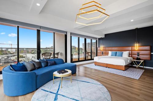 a bedroom with a blue couch and a bed at SOHO Hotel Auckland in Auckland