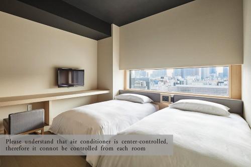 a hotel room with two beds and a window at ONSEN RYOKAN YUEN SHINJUKU in Tokyo
