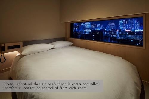 a bed in a room with a large window at ONSEN RYOKAN YUEN SHINJUKU in Tokyo