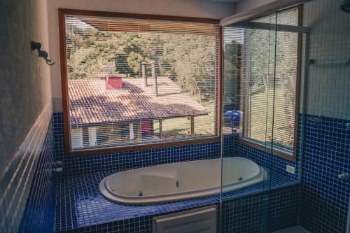 a bath tub in a bathroom with a window at Chacara da Dinda in Piraquara